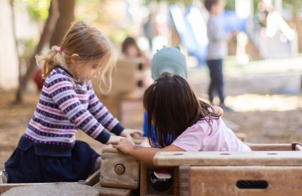 Two children working together at the outdoor play kitchen
